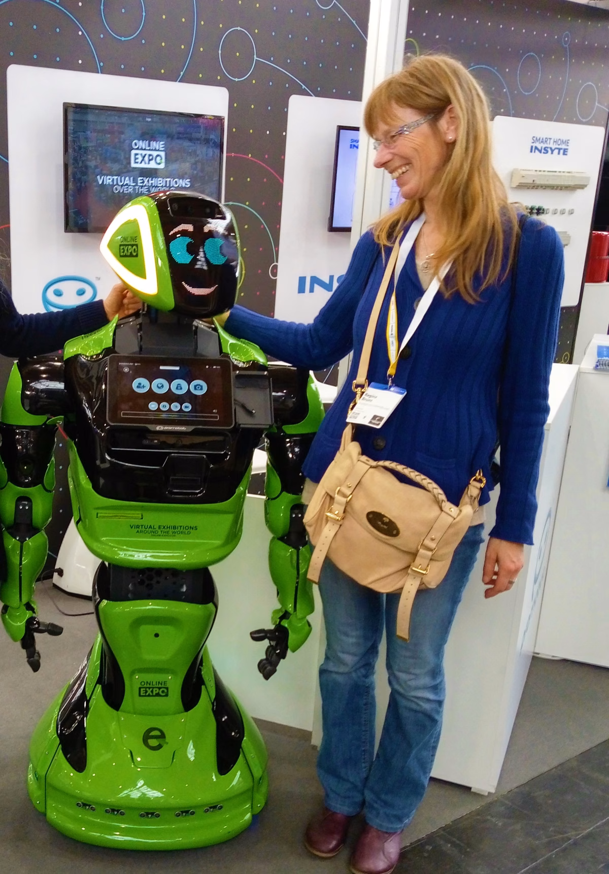 Regina Bostelmann steht neben einem humanoiden Roboter. Beide sind vollständig zu sehen.